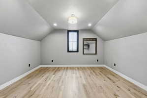 Room featuring a vaulted ceiling and light wood-finish flooring