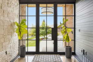 Entryway featuring a black-framed glass door system, stone veneer wall, and horizontal wood-finish paneling