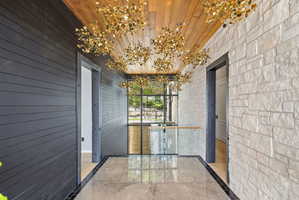 Entryway featuring a wood-finish ceiling, multiple gold-finish pendant light fixtures, and a glass railing