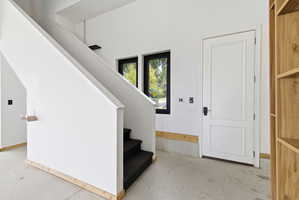 Carpeted stairs with a white banister and light wood trim, featuring twin windows with black frames