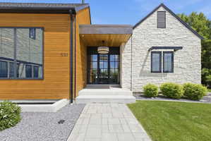 Modern exterior with a stone facade, wood siding, and large black-framed windows