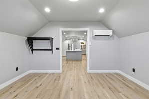 Attic space with light wood-finish flooring, white baseboards, and a wall-mounted shelving unit