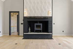 Central fireplace featuring a black wood-burning stove, natural stone hearth, and a textured tile surround extending to the vaulted ceiling
