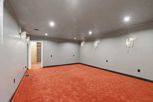 Spacious room featuring patterned orange carpeting, recessed ceiling lighting, and multiple decorative wall sconces