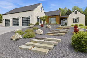 Modern exterior featuring light-colored stone siding, a dark roof, and wood-finish paneling