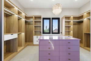 Custom walk-in closet featuring extensive built-in wood-finish shelving and hanging space with integrated lighting