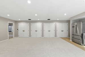 Spacious interior with neutral-toned walls, recessed lighting, and light-colored carpeting