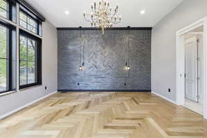 Herringbone wood-finish flooring provides a striking foundation for this room, complemented by a prominent gray brick accent wall