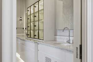 Bathroom vanity featuring a polished chrome faucet, under-mount sink, and light-toned countertop