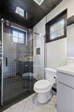 Contemporary bathroom featuring a glass-enclosed shower with a rainfall showerhead, dark wood-finish ceiling, and light gray herringbone tile flooring