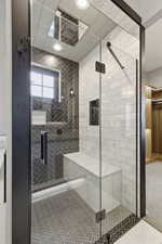 Glass-enclosed shower featuring a built-in bench, herringbone pattern tile flooring, and contrasting subway tile walls