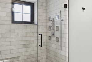 Glass-enclosed shower featuring subway-style tiling, a multi-setting shower system, and a black-framed window