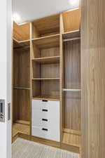 Custom closet system featuring wood-finish cabinetry, integrated shelving, hanging rods, and four white drawers with dark hardware