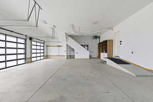 Spacious garage featuring a concrete floor, two modern glass-paneled garage doors, white painted walls, and an interior ramp