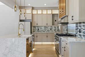 Modern kitchen featuring a waterfall island with an integrated farmhouse sink and brass-finish faucet