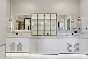 Dual vanity with white cabinetry, stone countertops, and subway tile backsplash