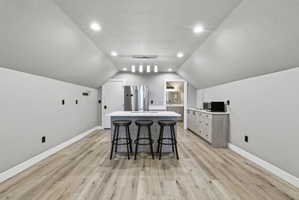 Spacious room featuring wood-finish flooring, recessed lighting, and a contemporary island with seating