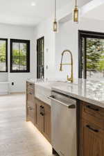 Kitchen island featuring a white apron-front sink, a brass-tone faucet, and stainless steel dishwasher