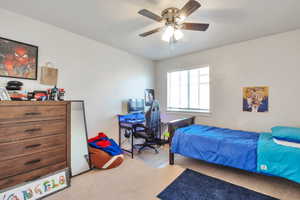 Bedroom featuring a ceiling fan with integrated lighting, a window with horizontal blinds, and neutral-toned wall paint