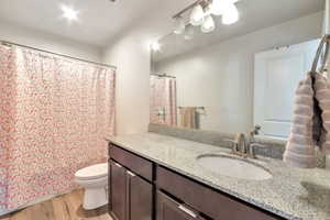Bathroom featuring a single vanity with a light granite-style countertop, undermount sink, and brushed nickel faucet