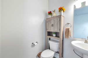Pedestal sink with stainless steel faucet, wall-mounted mirror, and overhead vanity lighting