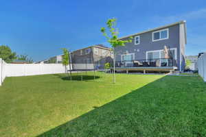 Spacious backyard featuring a large lawn area and white privacy fencing
