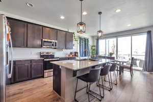 Kitchen featuring wood-finish flooring, dark cabinetry, and light-toned countertops