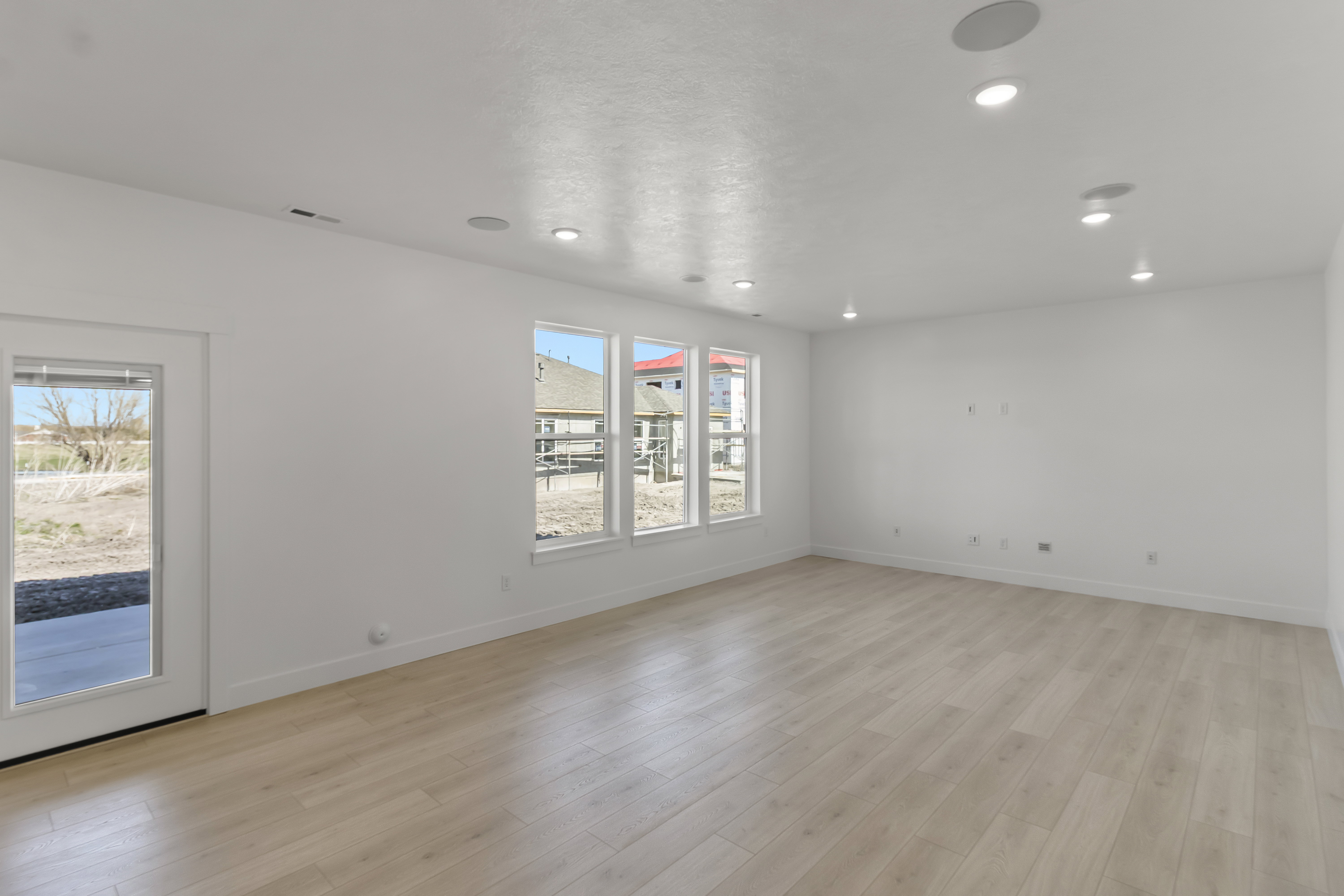 Spacious room featuring light wood-finish flooring, recessed lighting, and crisp white walls