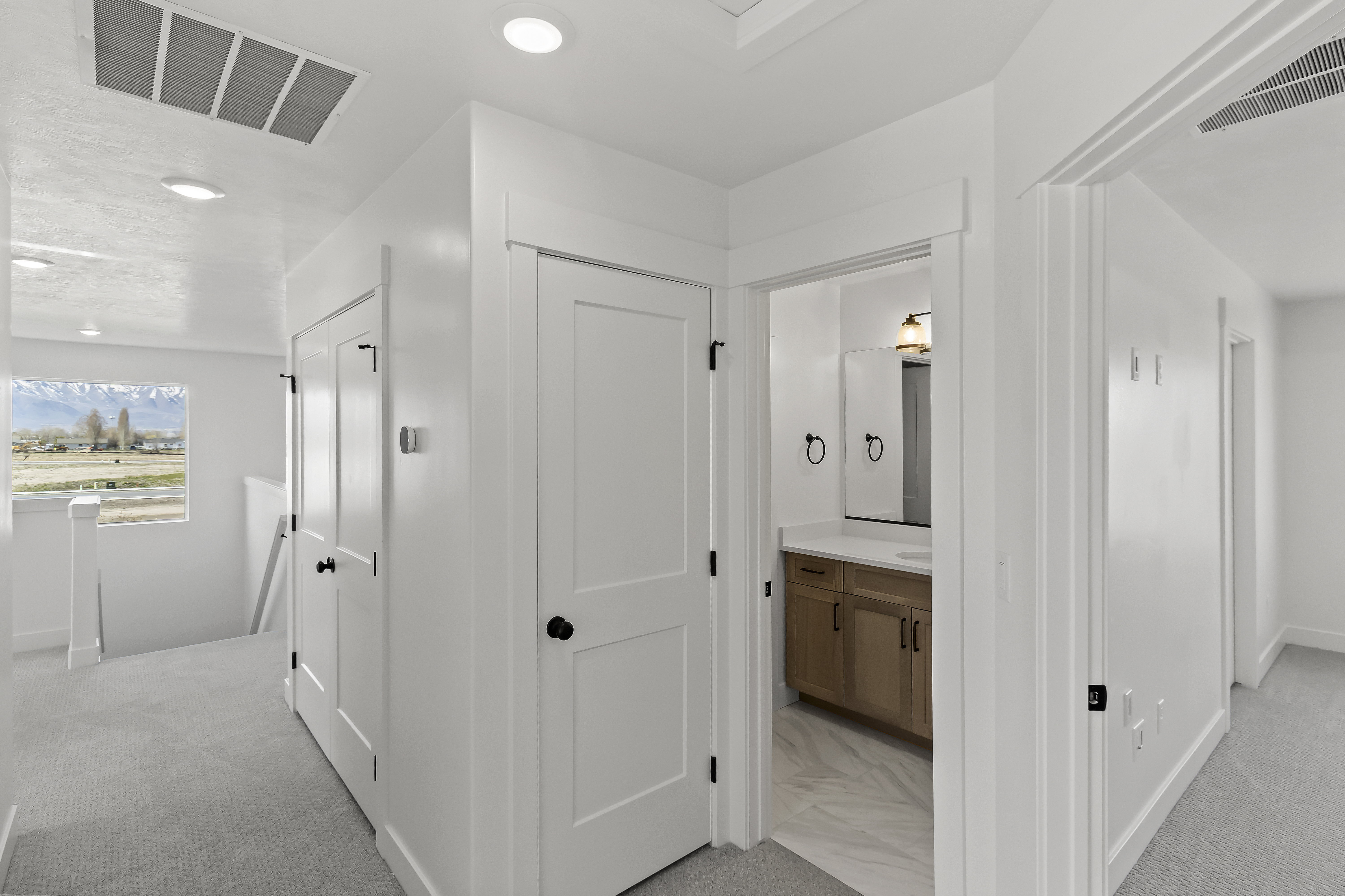 Hallway with light gray carpeting, recessed lighting, and a window offering a mountain landscape