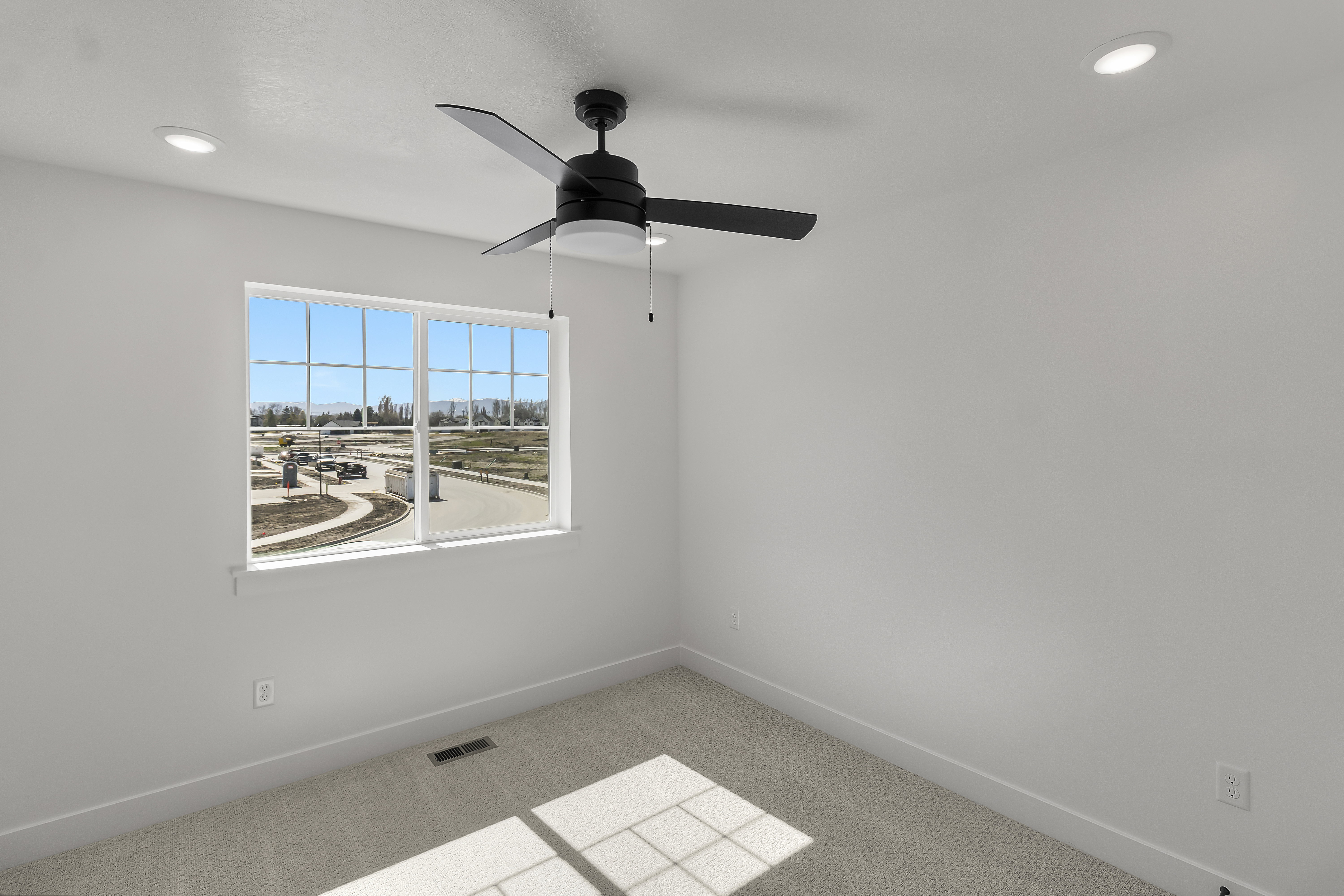Bright room featuring a large window, neutral carpeting, a contemporary black ceiling fan with light, recessed ceiling lighting, and white walls