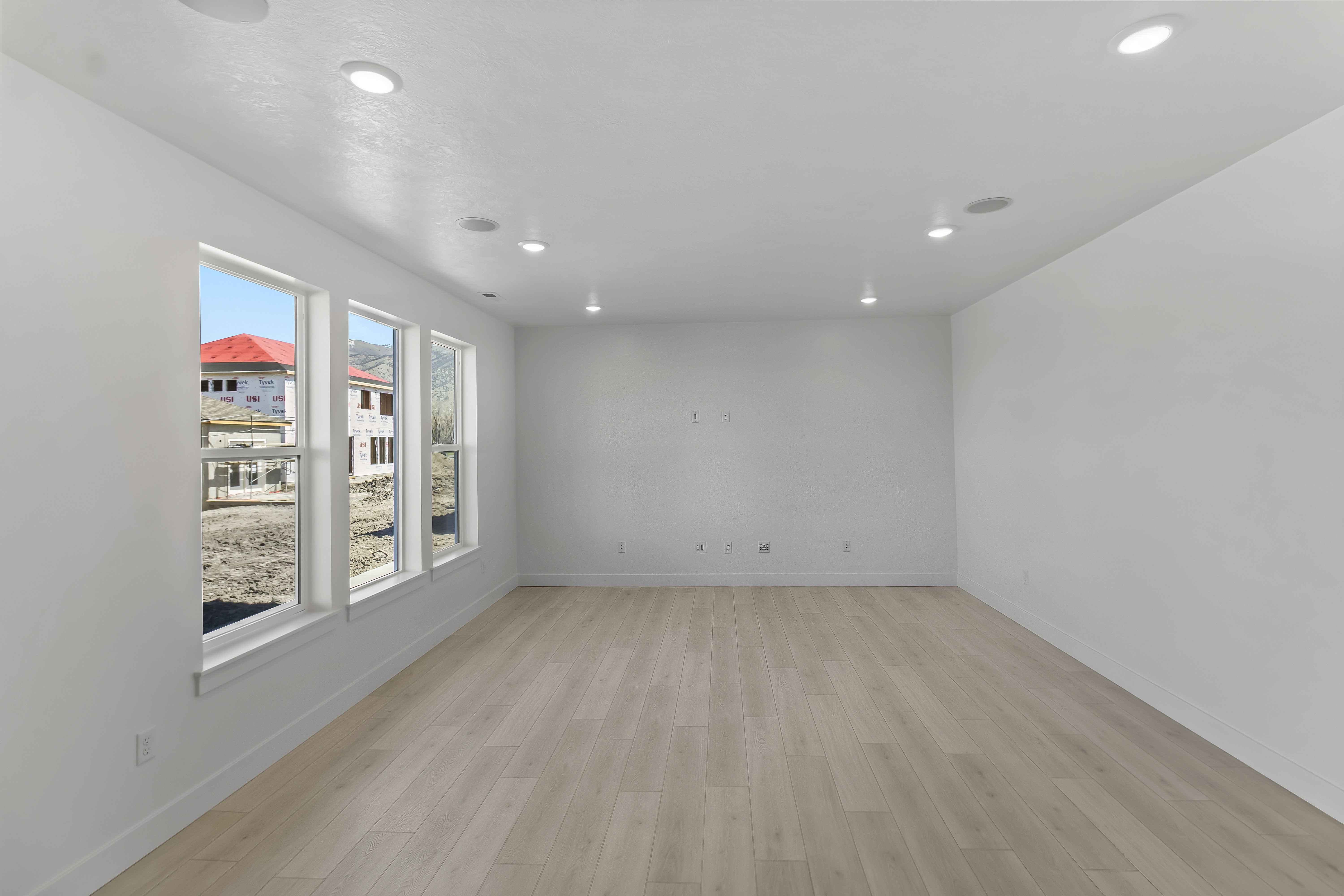 Spacious room featuring light wood-finish flooring, recessed lighting, and multiple windows