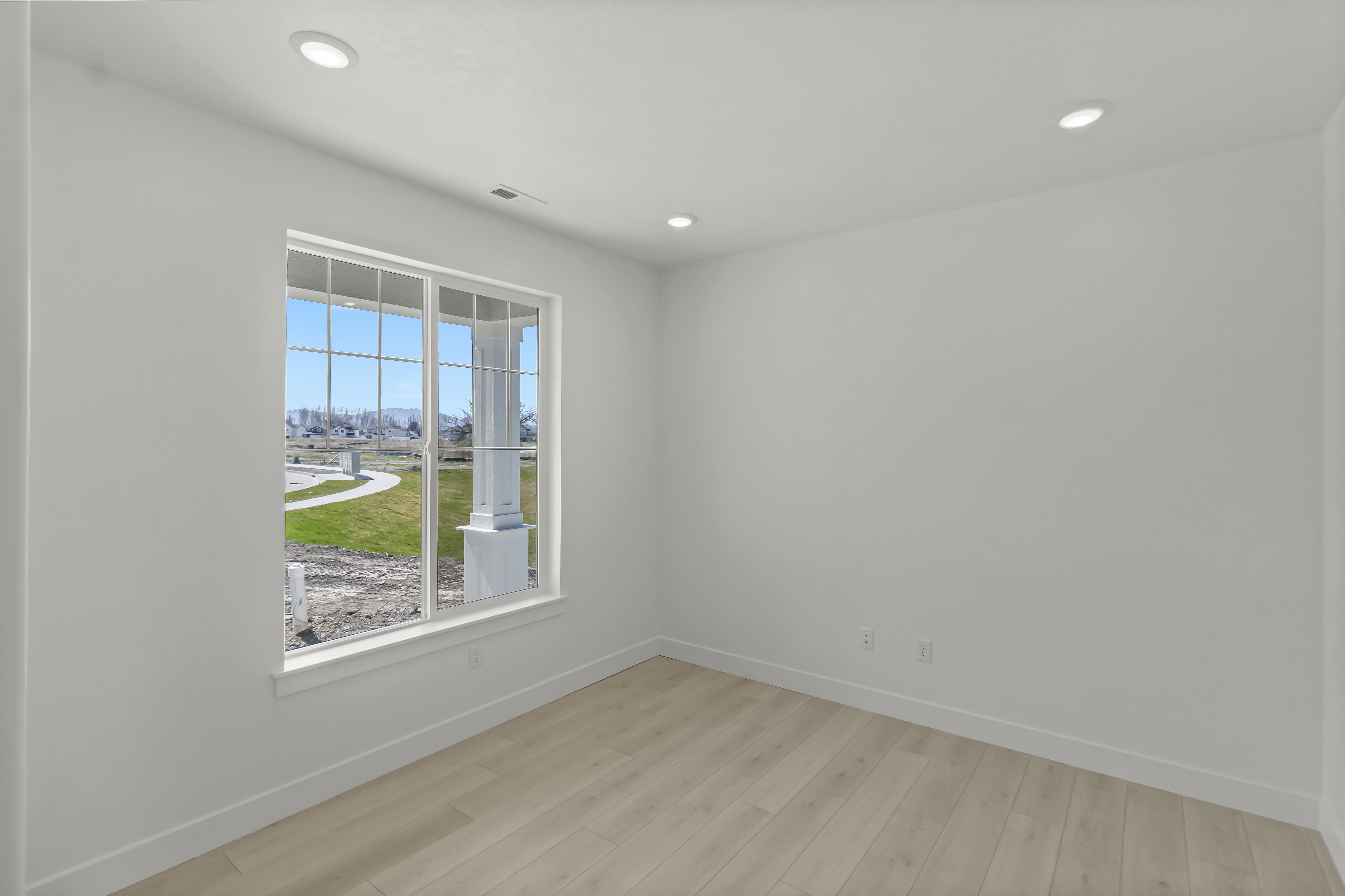 Bright room featuring a large multi-pane window, recessed lighting, light wood-finish flooring, white walls, and white baseboards