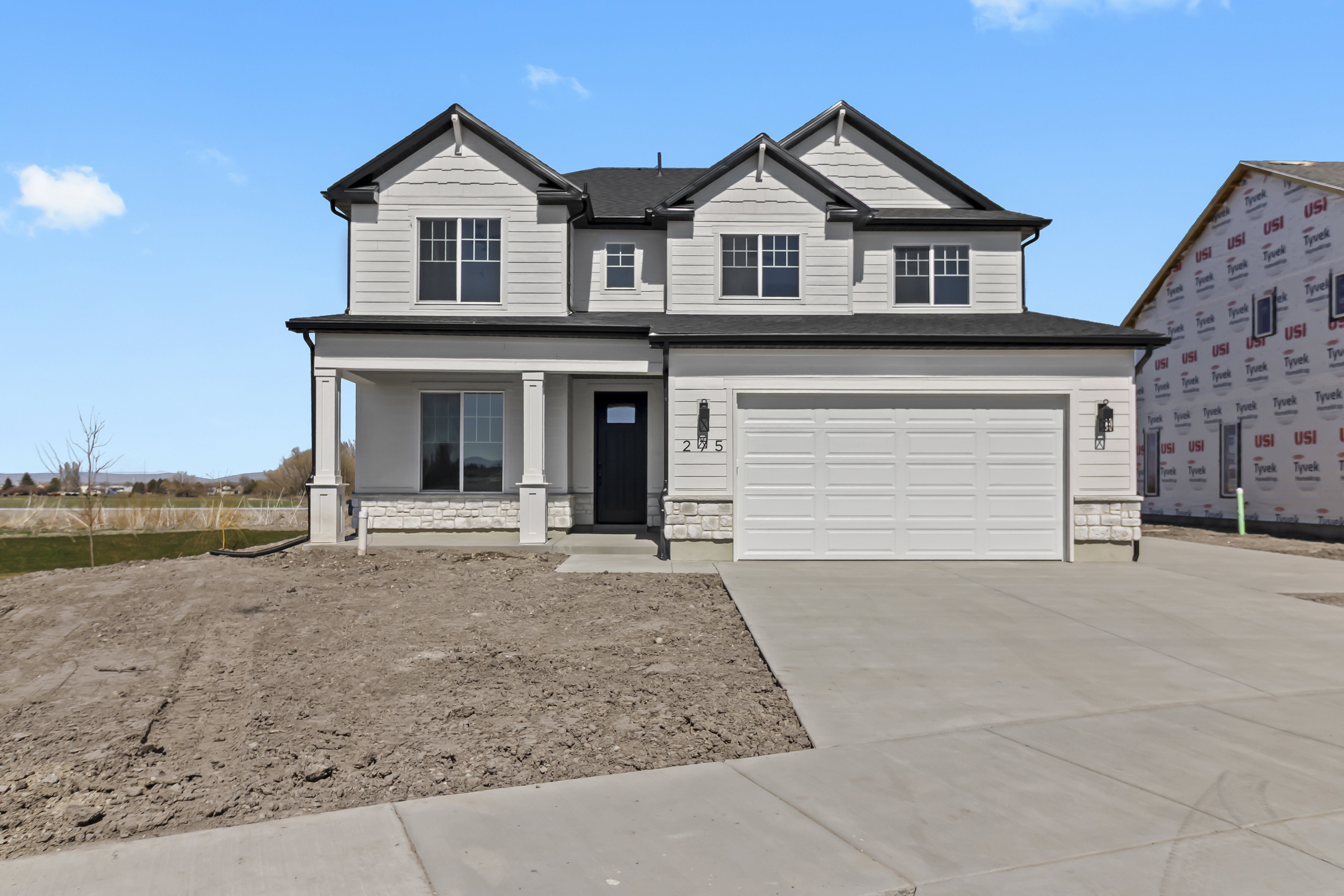Modern farmhouse exterior featuring light siding, dark trim, and a covered porch with square columns
