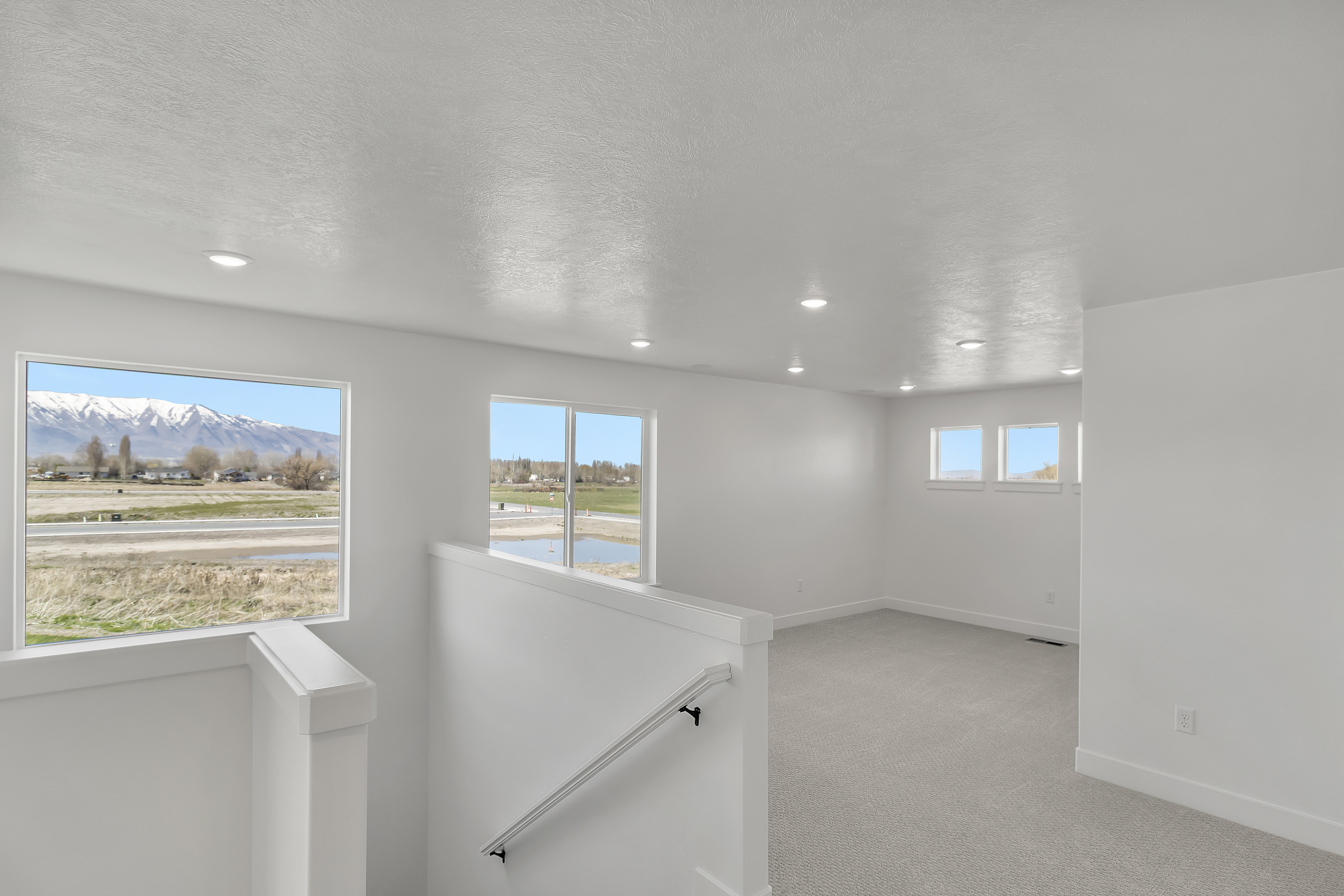 Upper-level living area featuring carpet flooring, recessed lighting, and multiple windows