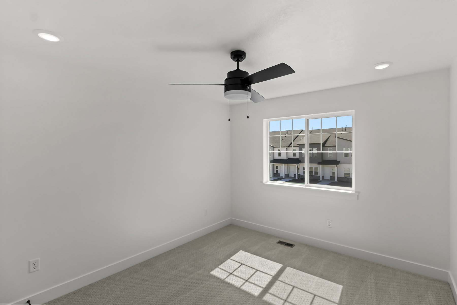 Bedroom featuring a black ceiling fan, two recessed lights, a window with grid panes, and neutral carpet flooring