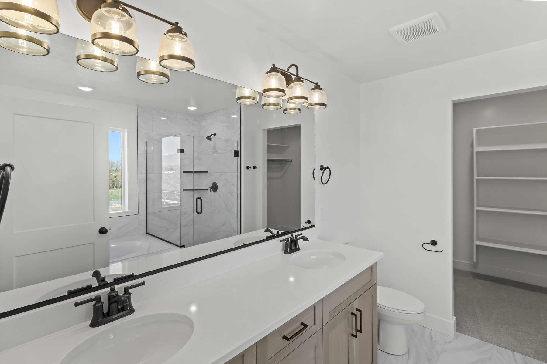 Bathroom featuring a double vanity with stone-finish countertop, matte black hardware, and an expansive mirror