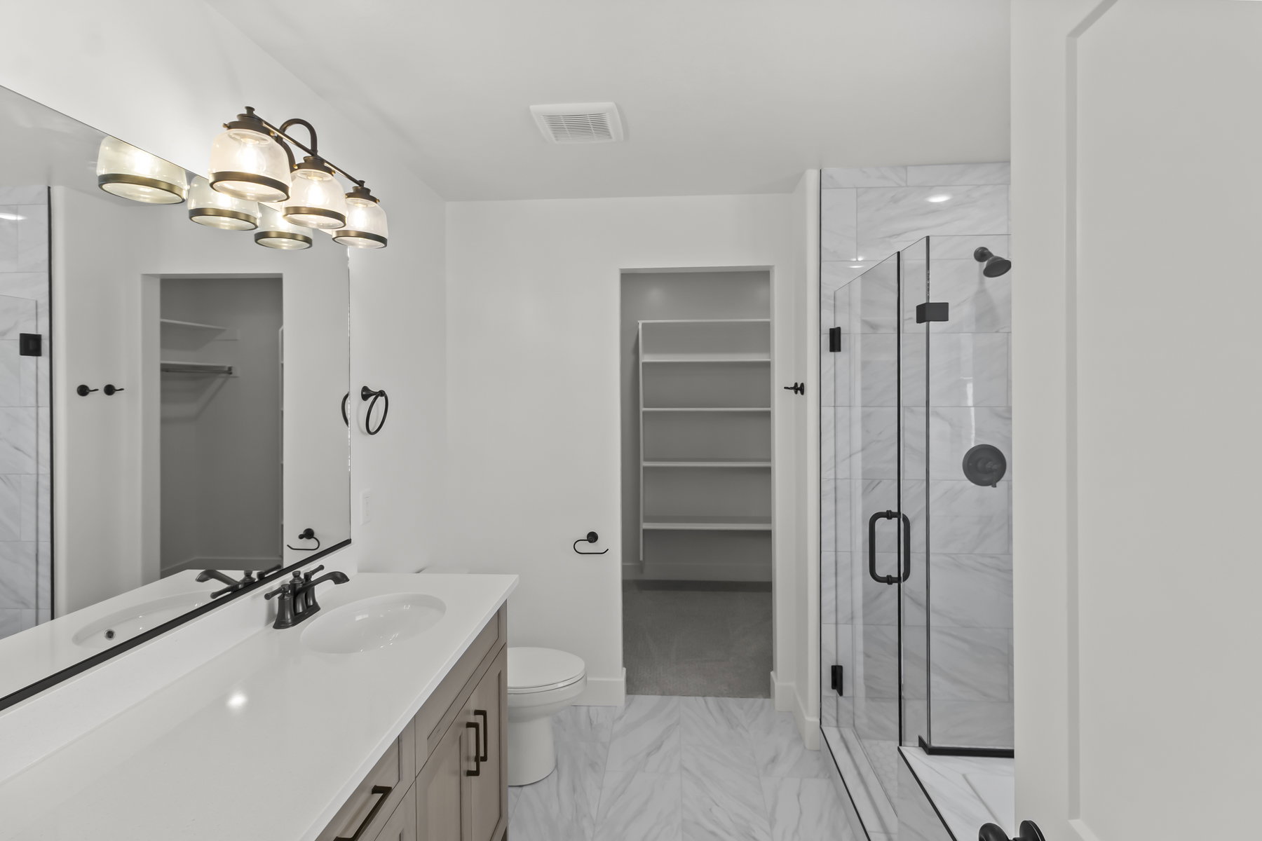Modern bathroom featuring a double vanity with stone-finish countertop, dual sinks, and matte black fixtures