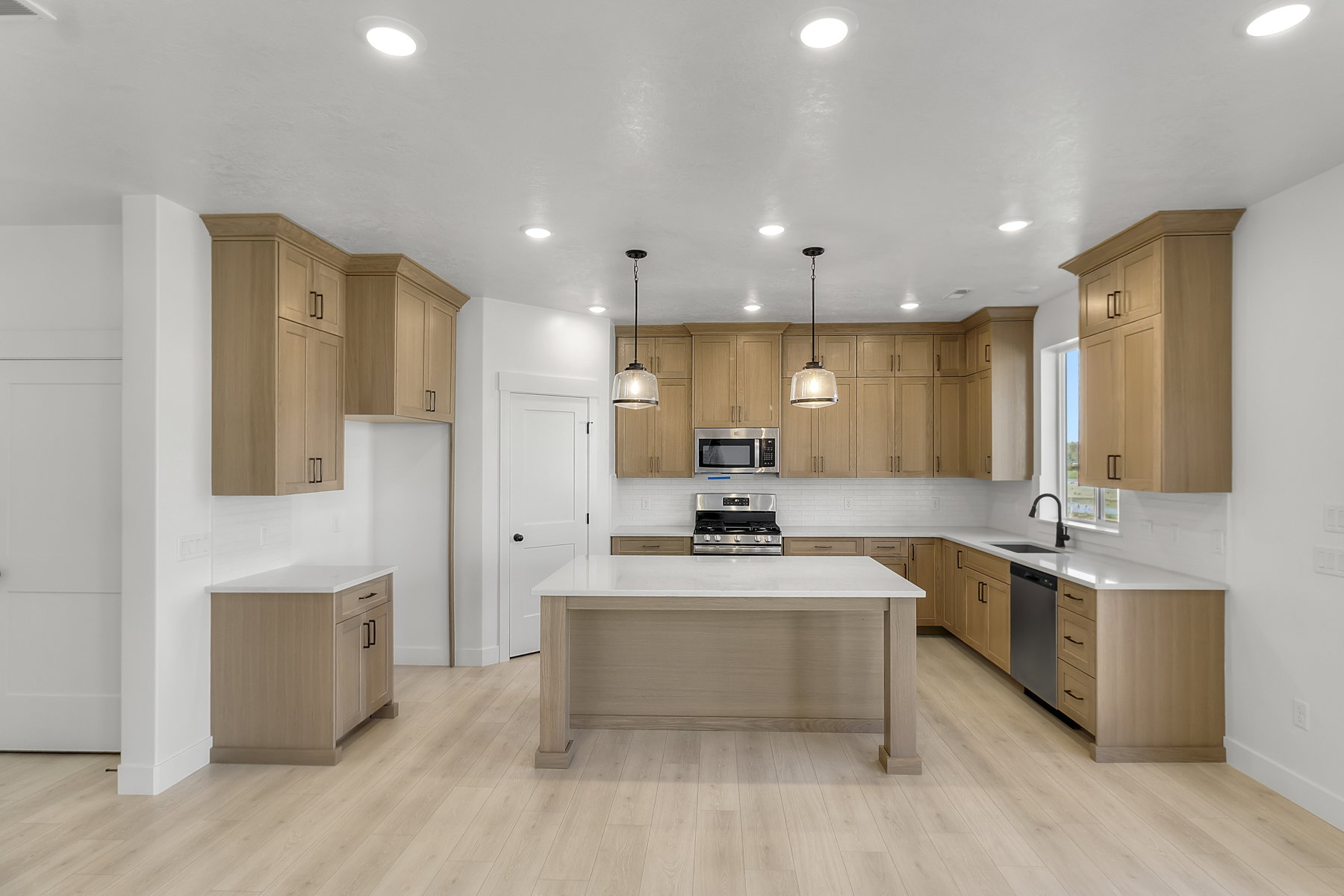 Bright kitchen featuring light wood-finish cabinetry, white countertops, and a subway tile backsplash