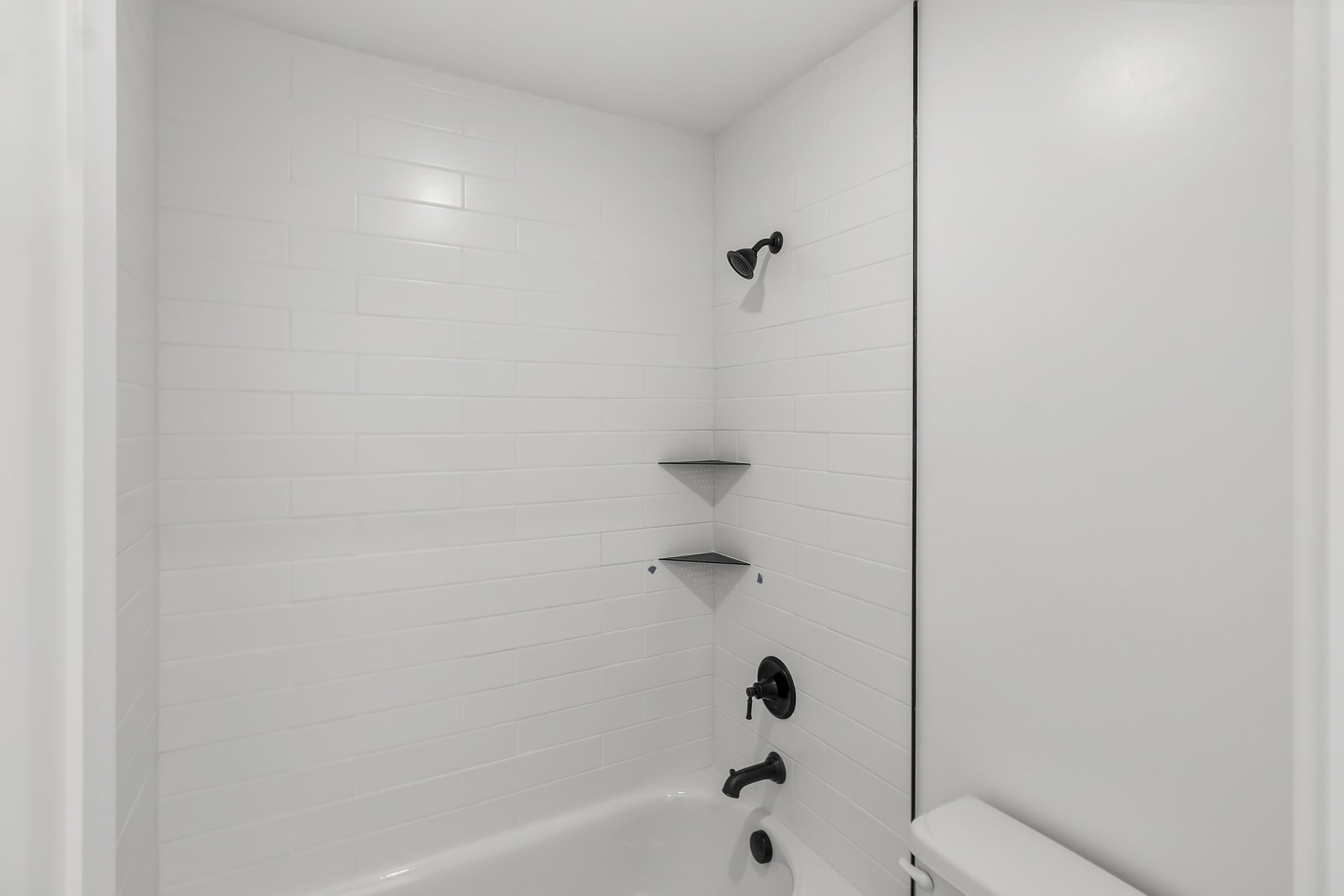 Bathroom featuring a white subway tile shower surround with integrated corner shelves