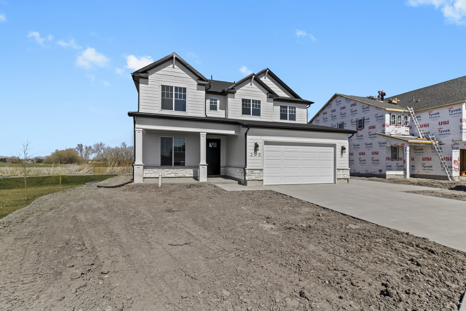 Contemporary two-story residence featuring light siding, dark trim, and a prominent two-car garage