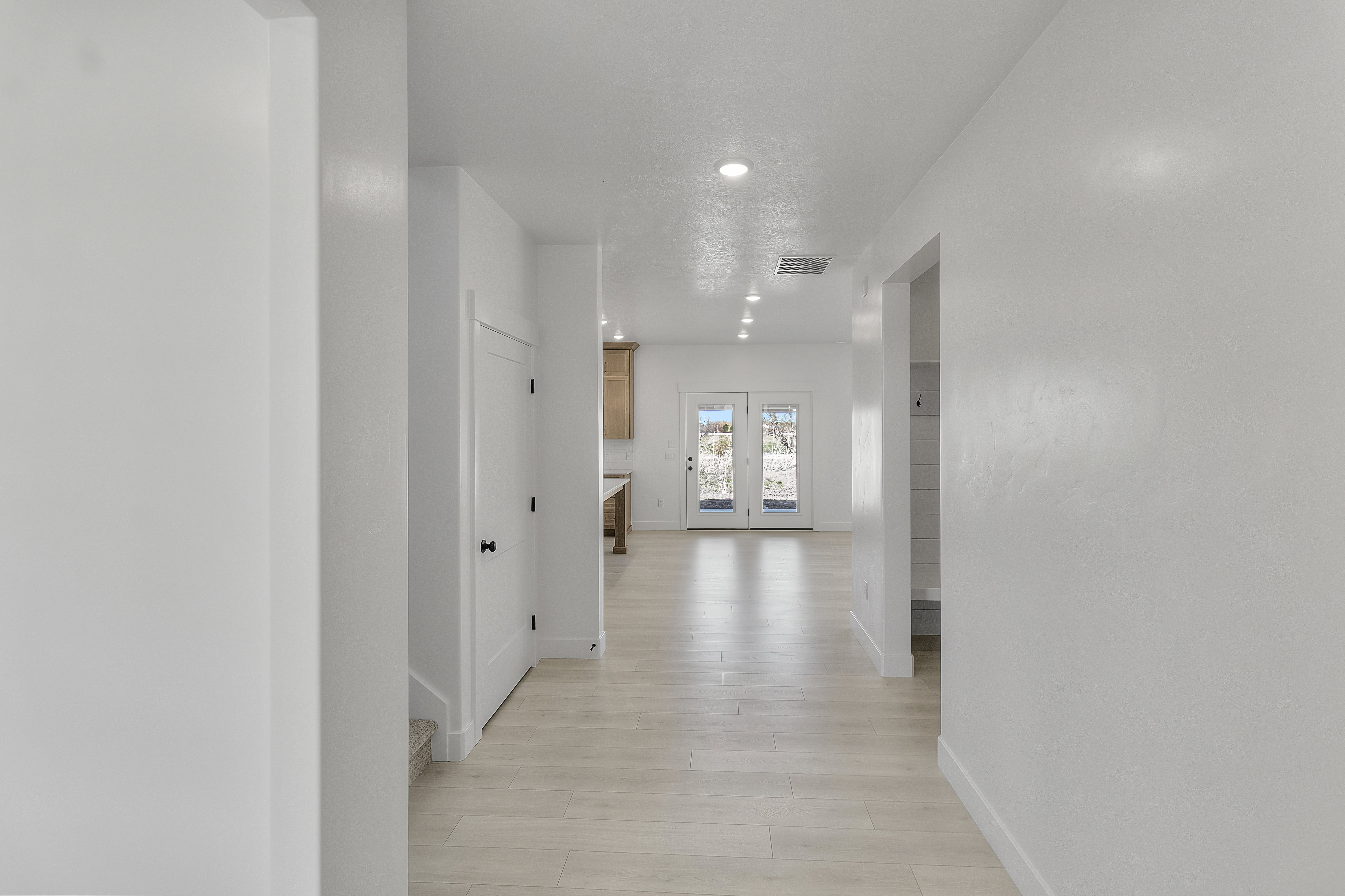 Hallway featuring light wood-finish flooring, white walls, and recessed lighting