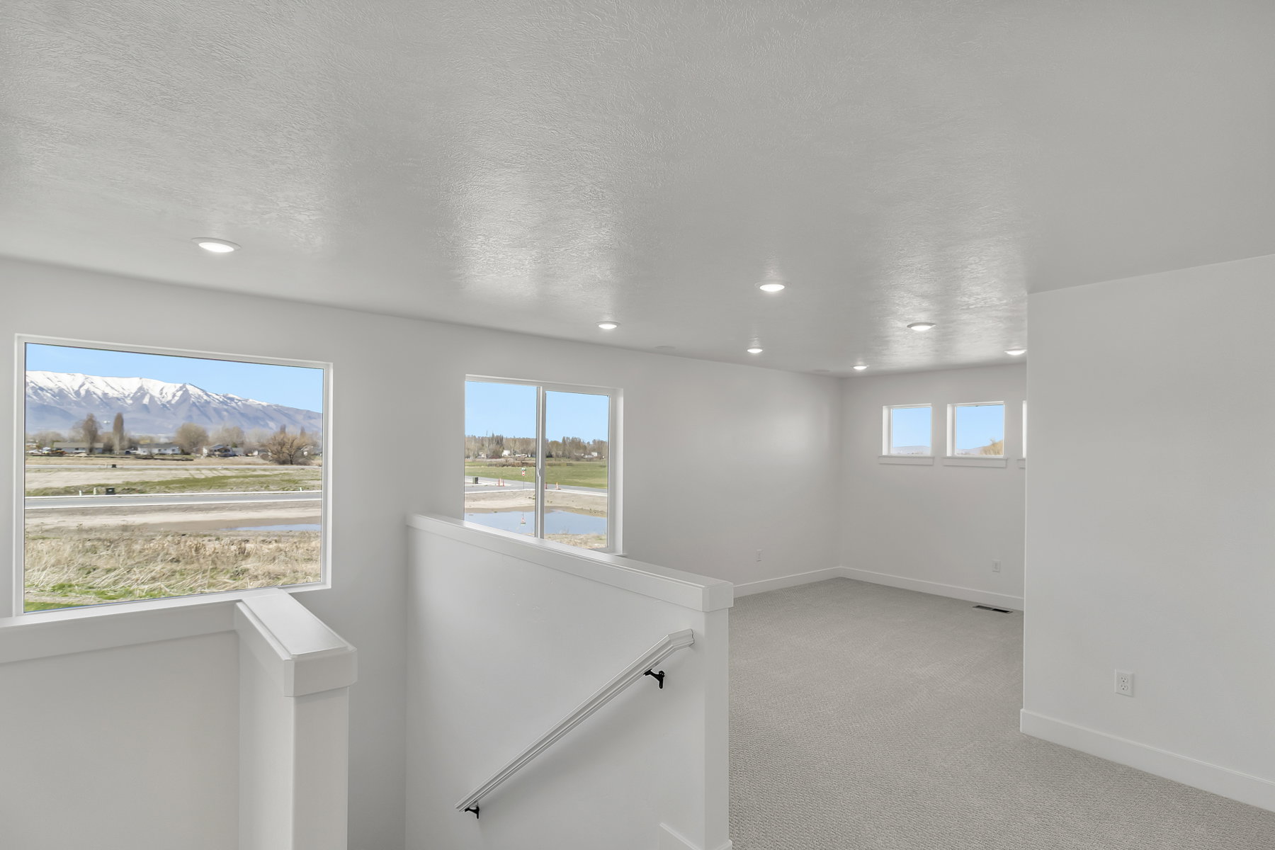Spacious interior featuring a carpeted floor, recessed lighting, and multiple windows offering mountain and landscape scenery