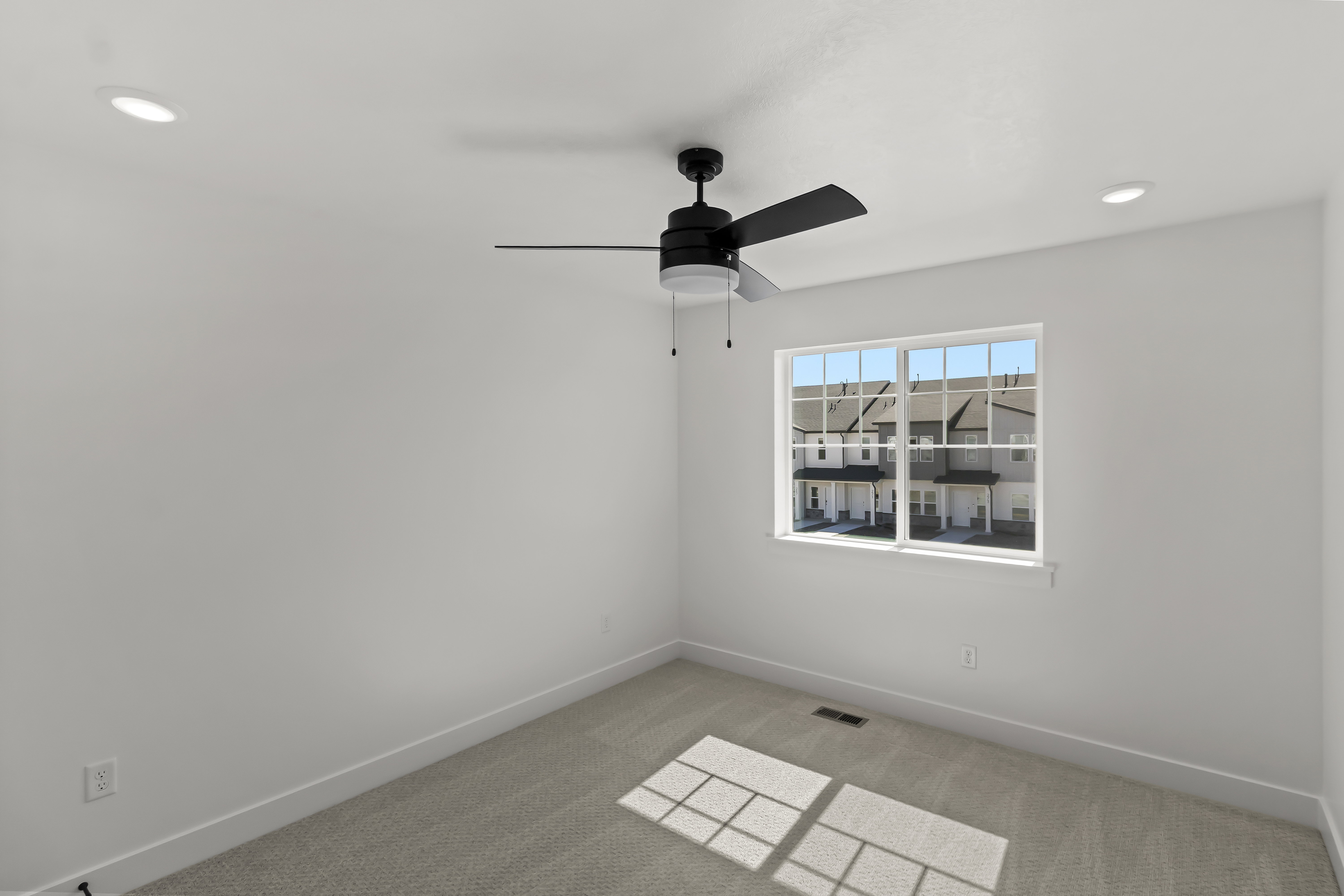 Bright room featuring white walls, a multi-pane window, and light-colored carpeting