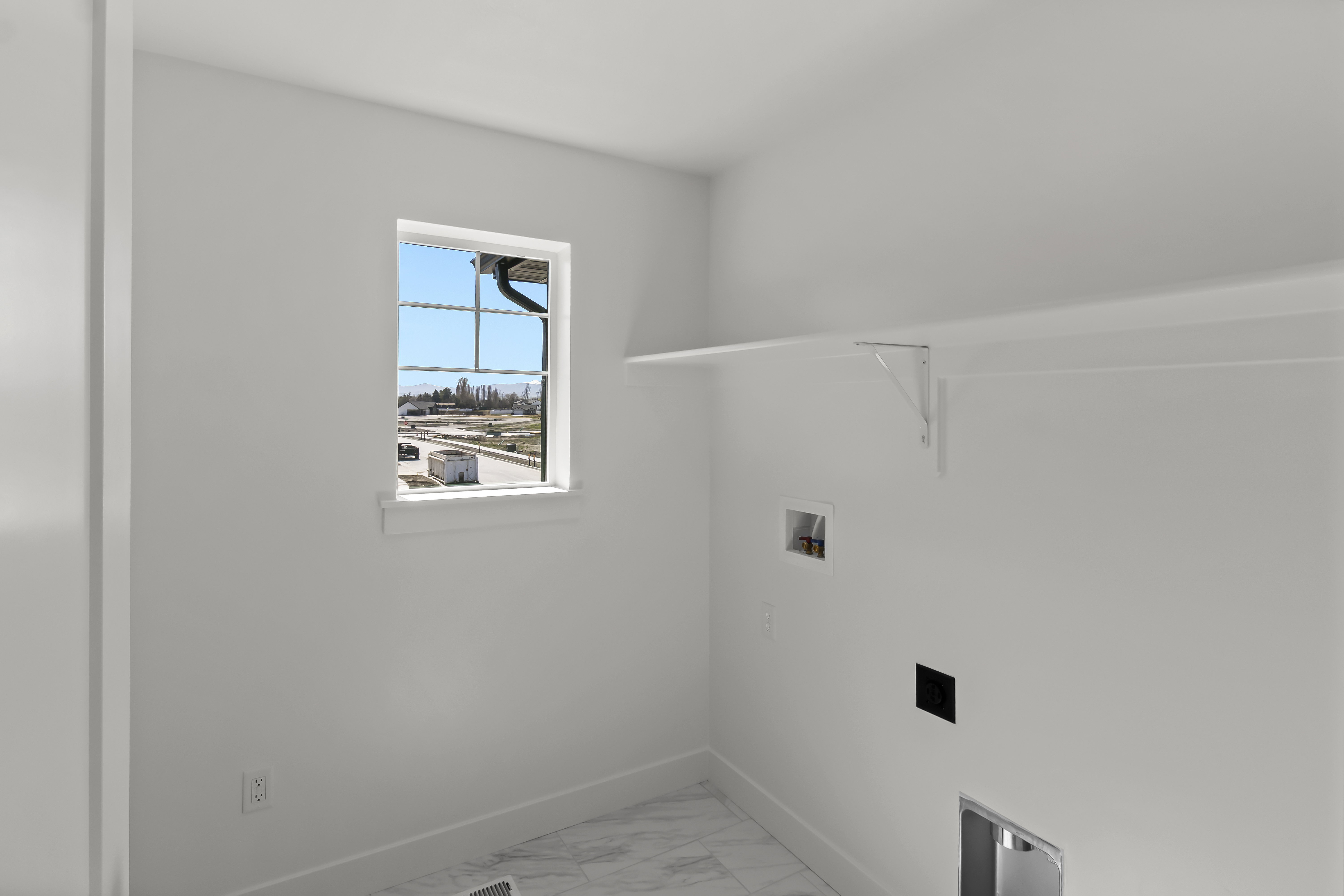 Utility space featuring a window, pre-installed shelving, and laundry hookups