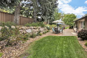 Expansive backyard featuring a manicured lawn, a large stamped concrete patio, and a stone retaining wall