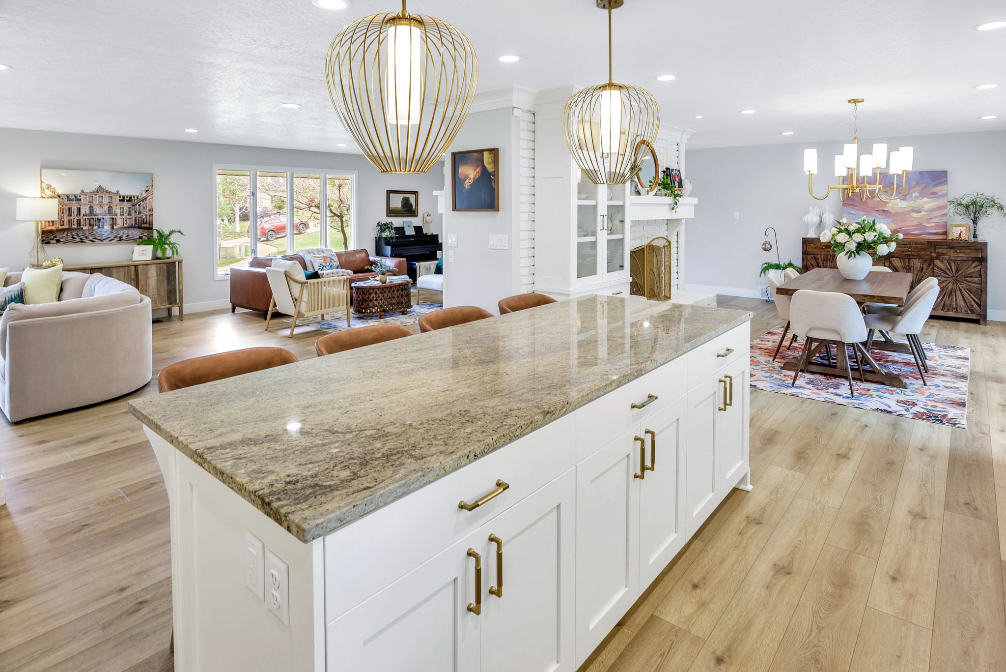 Spacious open-concept living area featuring an expansive kitchen island with a stone countertop, recessed lighting, and wood-finish flooring