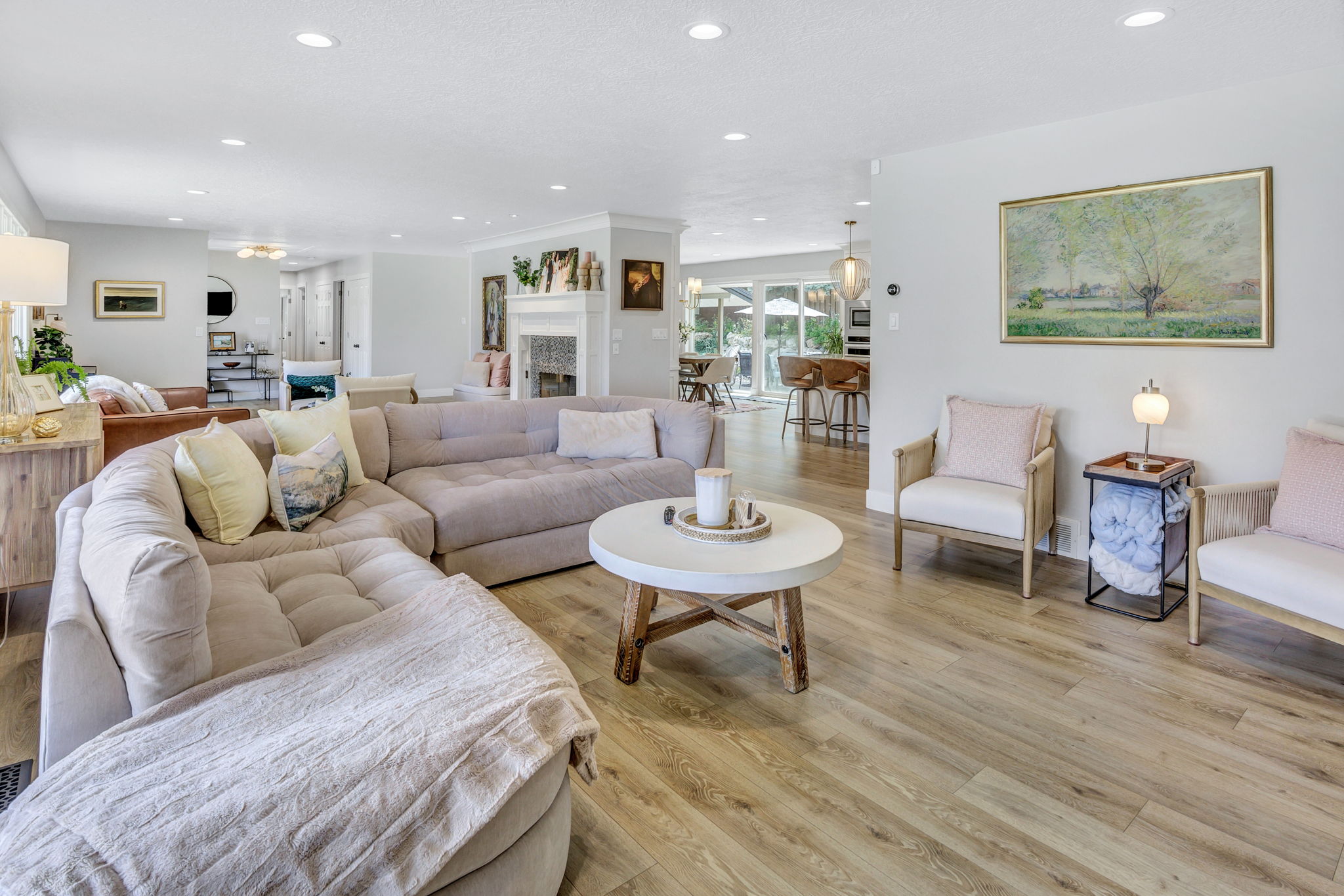 Open-concept living area featuring wood-finish flooring, recessed lighting, and a white fireplace surround