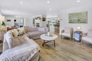 Open-concept living area featuring wood-finish flooring, recessed lighting, and a white fireplace surround