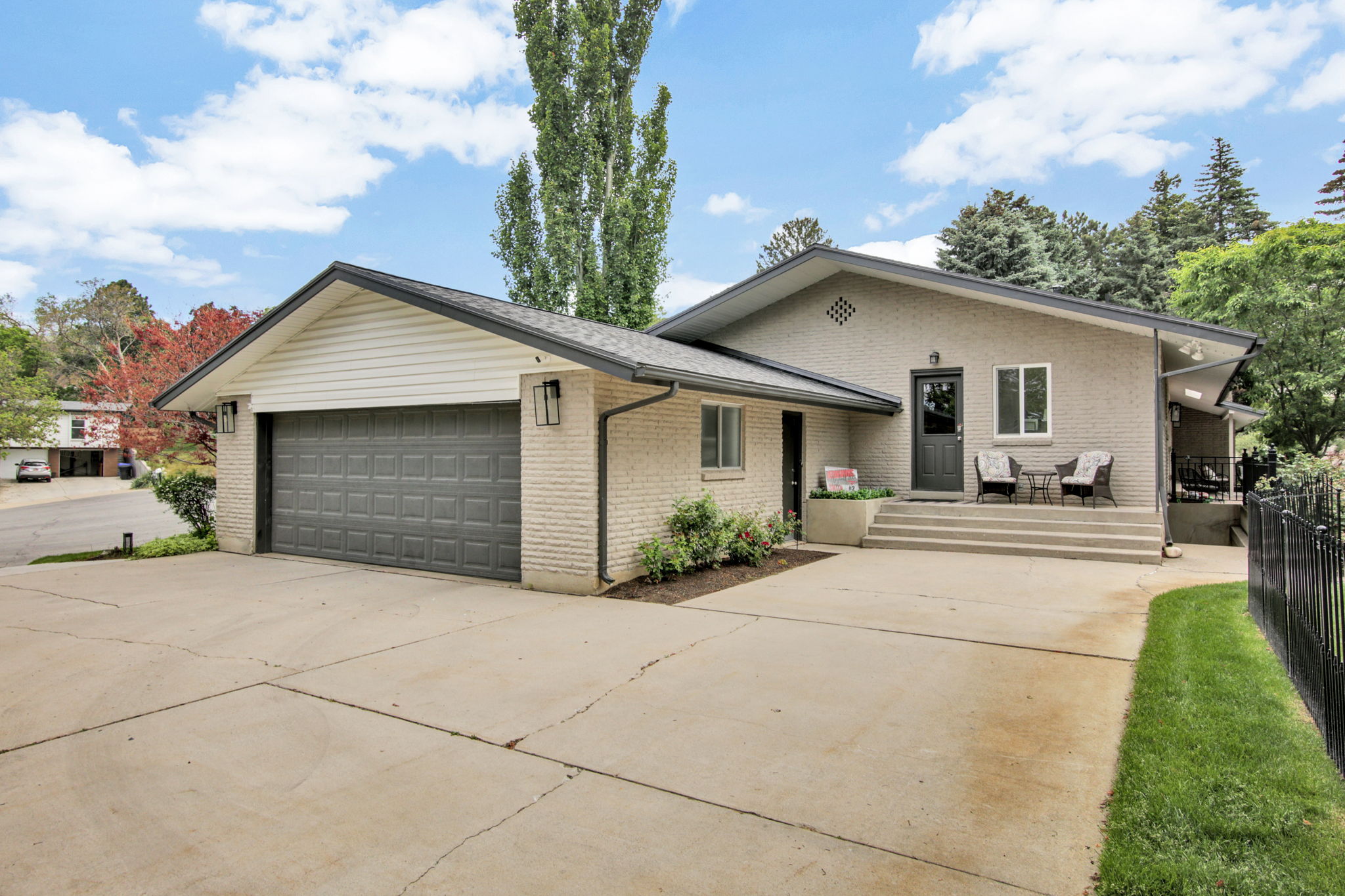 Brick exterior residence featuring an attached two-car garage with a dark gray door, a concrete driveway, and a front entry with steps