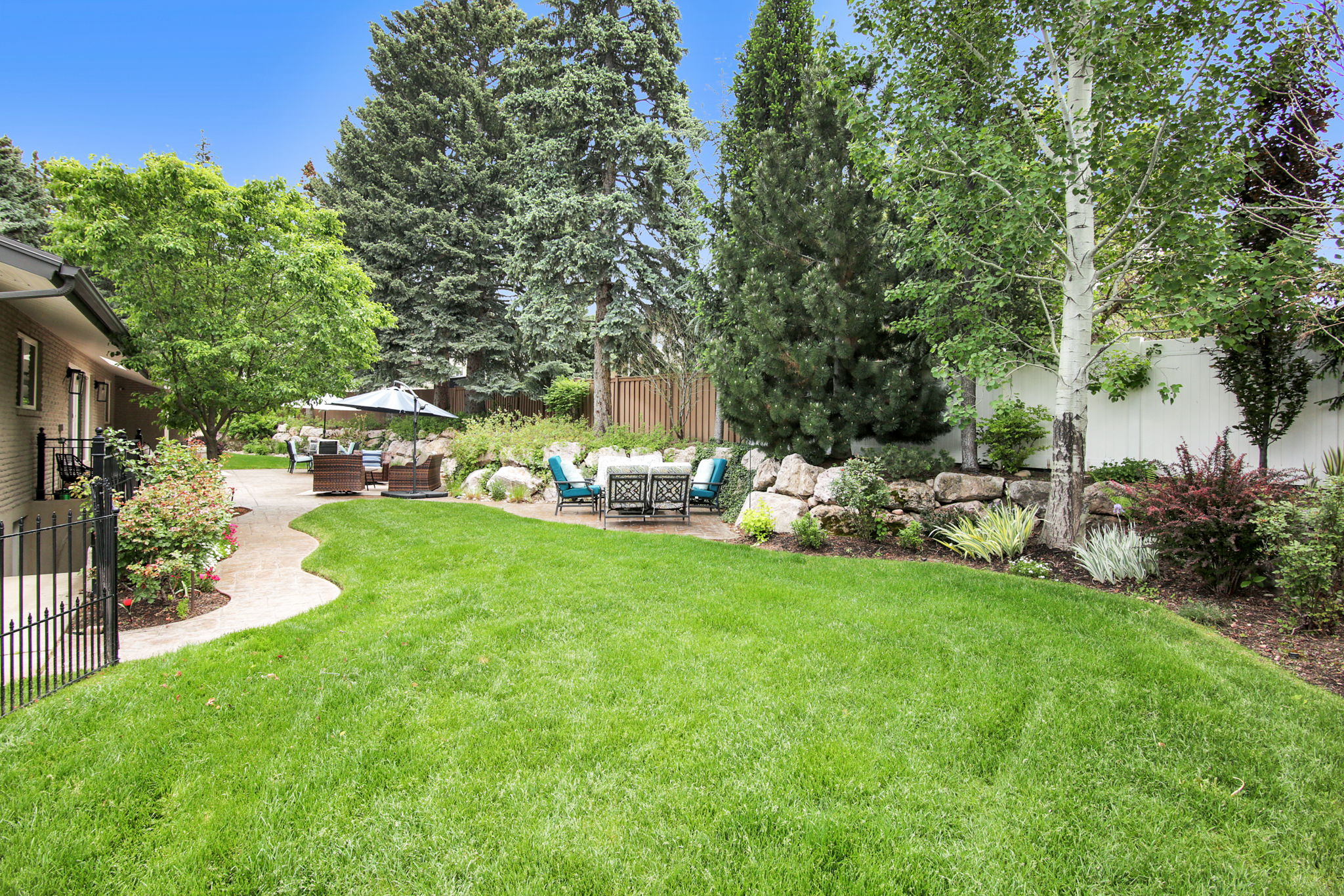 Spacious lawn area with a winding paved pathway leading to multiple outdoor patio areas